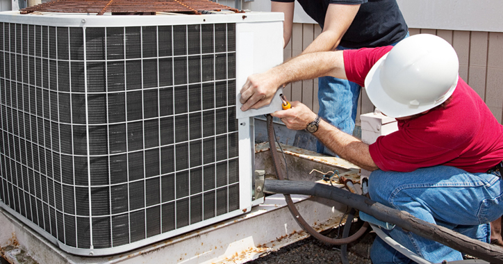 Two men working on an outdoor HVAC unit.